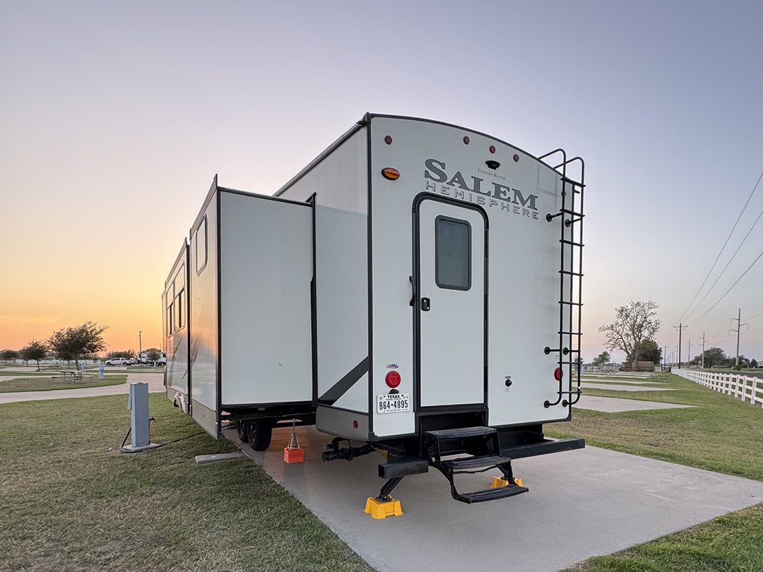 Salem Hemisphere RV trailer parked on a concrete pad at sunset, with a slide-out extended and a rear ladder. (Informative image)