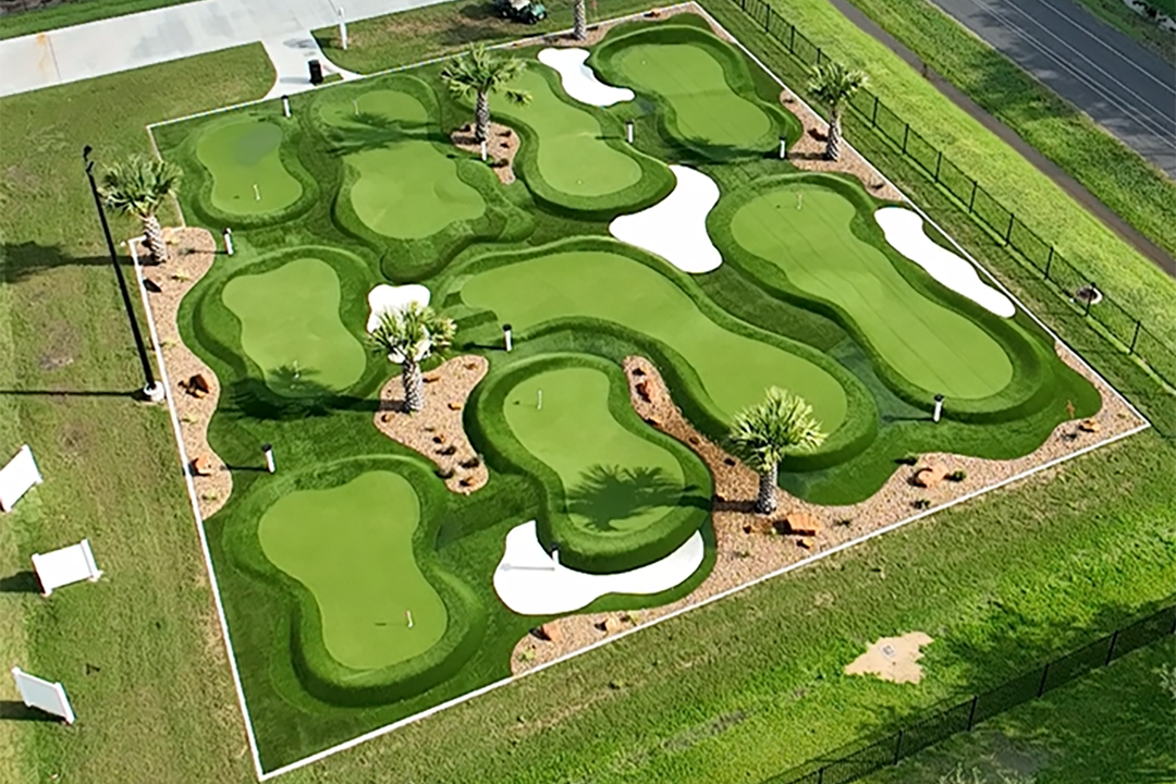 Aerial view of a miniature golf course with multiple greens, sand traps, and palm trees.